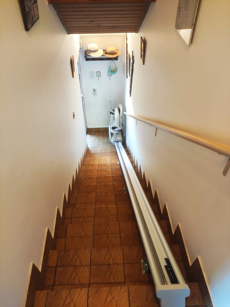 Monte-escalier droit avec accoudoirs et repose-pieds replié en bas d'un escalier