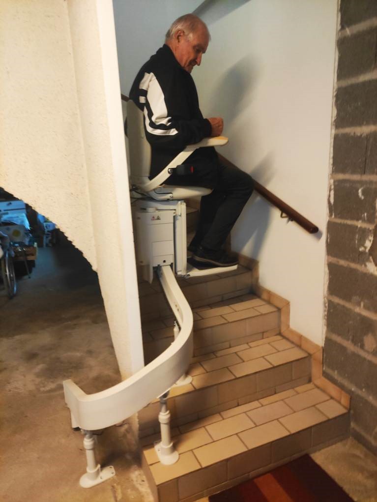 Monte-escaliers courbe installé sur un escalier en carrelage utilisé par une personne