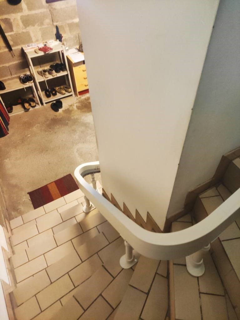 Rail d'un monte-escaliers courbe installé sur un escalier en carrelage