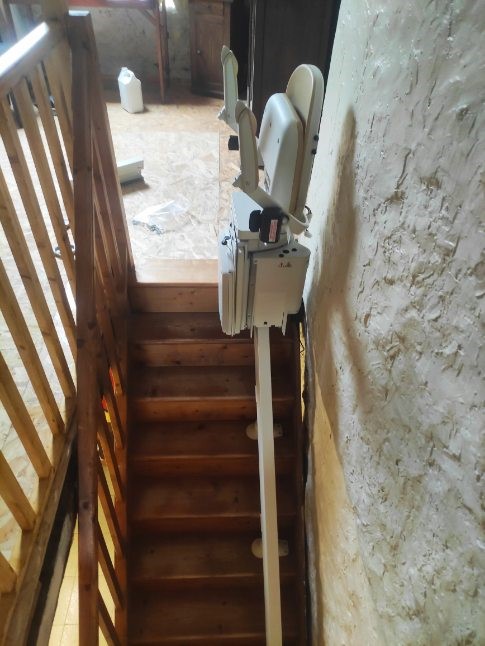 Monte-escaliers courbe en haut d'un escalier en bois avec les accoudoirs et le repose-pieds repliés