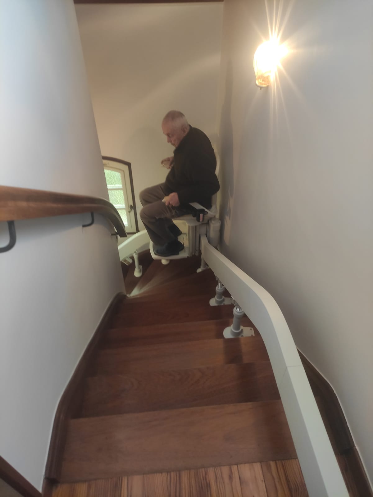 Personne utilisant un monte-escalier courbe dans un escalier étroit
